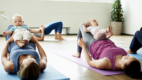 Women on yoga mats doing pelvic floor exercises with their babies
